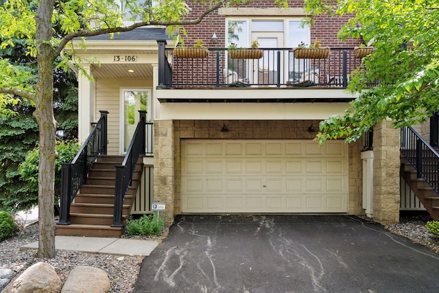 13 4th Ave N Unit 106, Minneapolis, MN 55401 - view of front of property with a garage, stairs, a balcony, driveway, and brick siding
