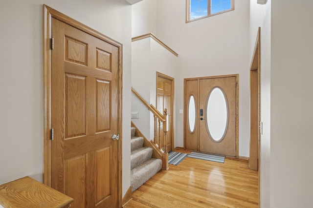 foyer featuring a high ceiling, light wood-style flooring, and stairs