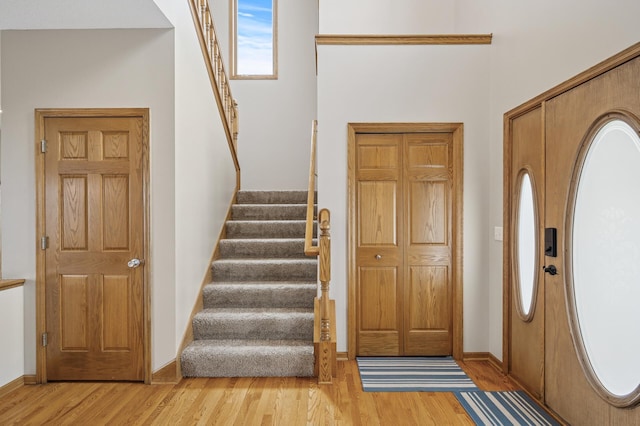foyer with baseboards, stairway, and light wood-type flooring