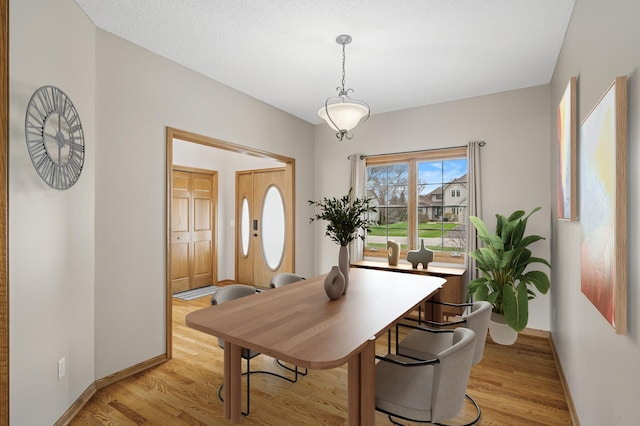 dining space with light wood finished floors and baseboards