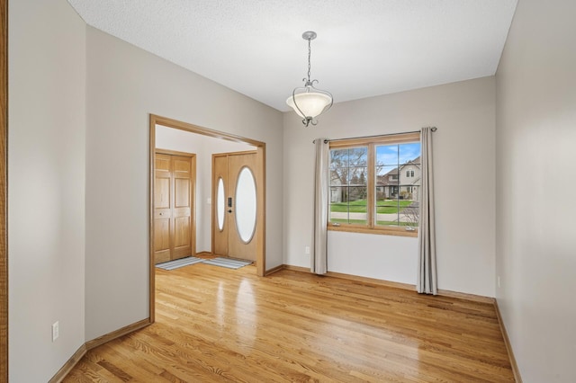 foyer with light wood-style flooring and baseboards