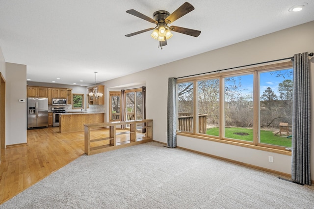 unfurnished living room featuring recessed lighting, a wealth of natural light, and baseboards