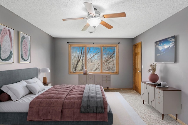 bedroom featuring a textured ceiling, a ceiling fan, light colored carpet, and baseboards