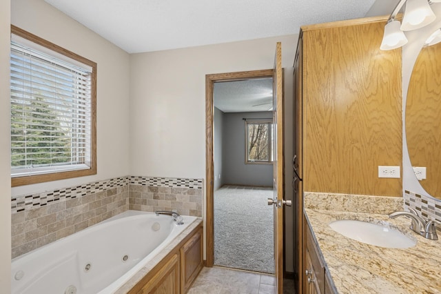 bathroom with a jetted tub, tile patterned floors, vanity, and plenty of natural light