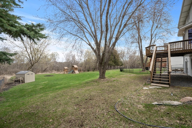 view of yard with an outdoor structure, a playground, a deck, a storage shed, and stairway