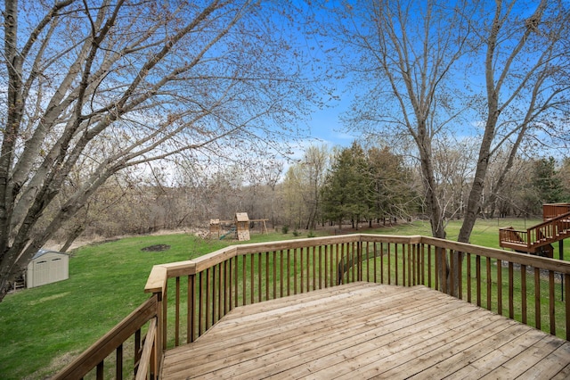 wooden terrace featuring a yard, an outbuilding, a shed, and a playground