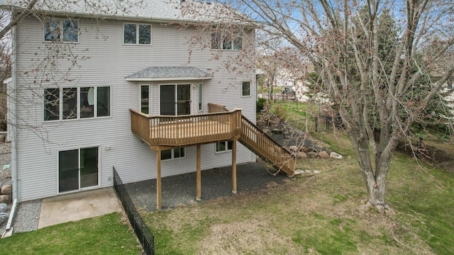 rear view of property with a deck, a yard, a patio, roof with shingles, and stairs