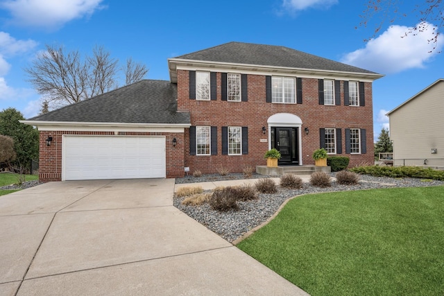 colonial inspired home with a front yard, a shingled roof, brick siding, and a garage