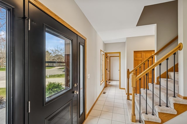 entrance foyer with baseboards, stairway, light tile patterned floors, and plenty of natural light