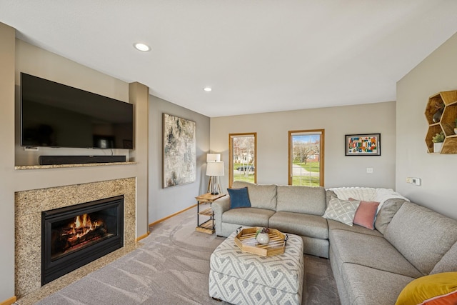 carpeted living area with baseboards, recessed lighting, and a glass covered fireplace