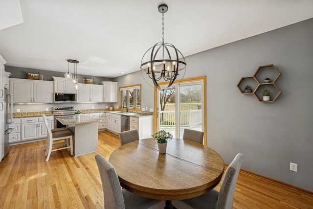 dining space with a chandelier, baseboards, and light wood-style floors
