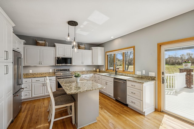 kitchen with appliances with stainless steel finishes, a center island, plenty of natural light, and a sink