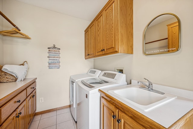 clothes washing area featuring light tile patterned floors, independent washer and dryer, a sink, baseboards, and cabinet space