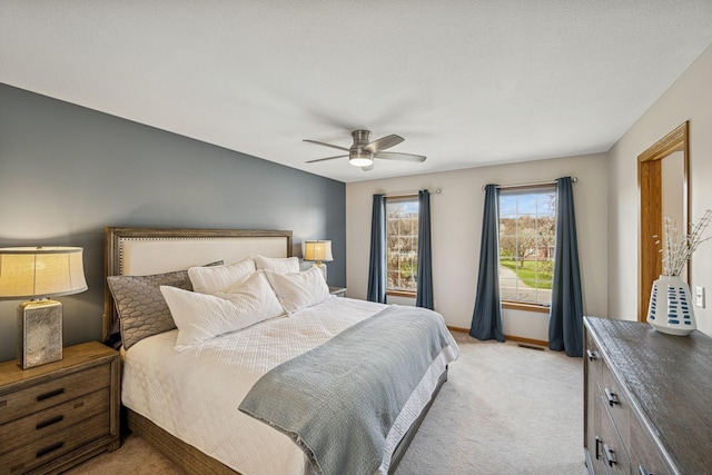 bedroom featuring a ceiling fan, visible vents, light colored carpet, and baseboards