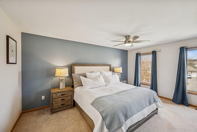 bedroom with baseboards, a ceiling fan, and light carpet