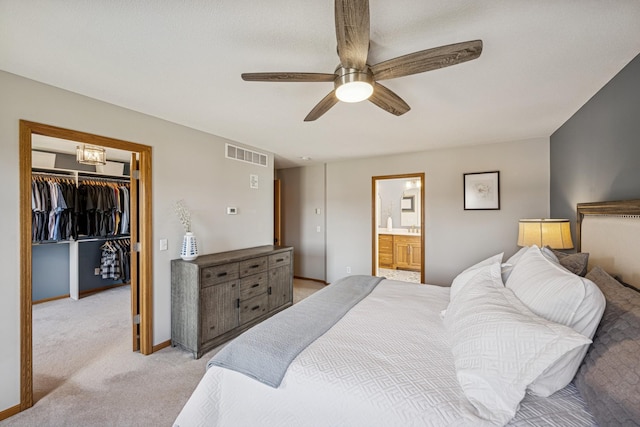 bedroom featuring light colored carpet, visible vents, a closet, a ceiling fan, and a walk in closet