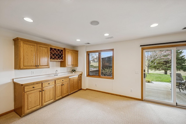 kitchen featuring light colored carpet, light countertops, baseboards, and a sink