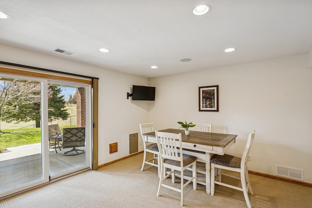 dining area with light colored carpet, visible vents, and baseboards