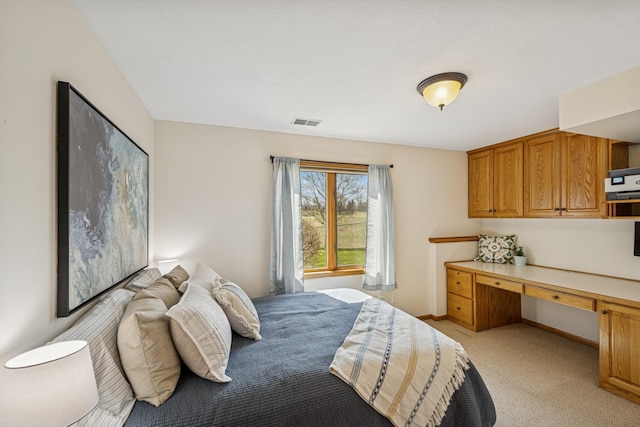 bedroom with baseboards, visible vents, light colored carpet, and built in study area