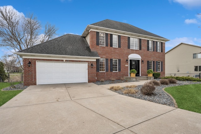 colonial house featuring brick siding, fence, a garage, roof with shingles, and concrete driveway