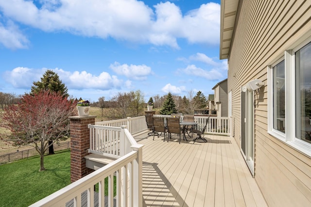 deck featuring a lawn, outdoor dining space, and fence