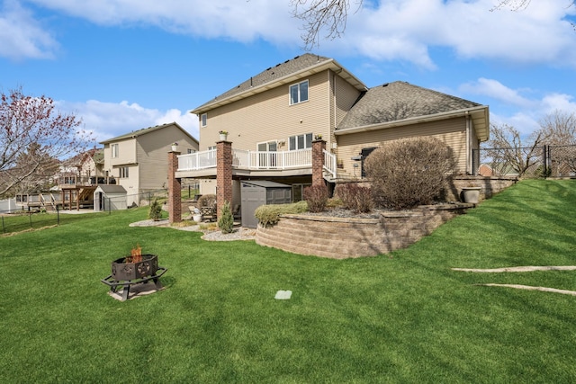 back of property featuring an outdoor fire pit, an outdoor structure, a fenced backyard, a shed, and a deck