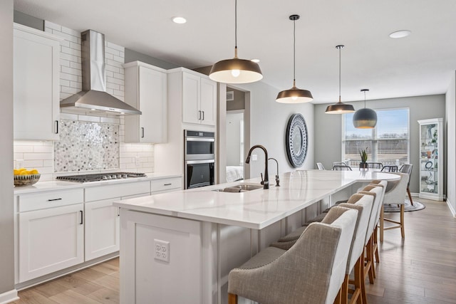 19477 102nd Pl, Corcoran, MN 55374 - kitchen featuring wall chimney range hood, stainless steel appliances, tasteful backsplash, light wood-type flooring, and recessed lighting