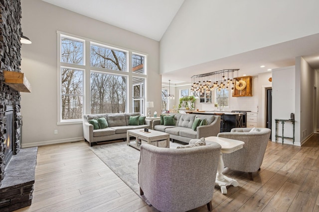 18837 Ogden St NW, Elk River, MN 55330 - living area featuring a stone fireplace, light wood-style floors, high vaulted ceiling, and baseboards