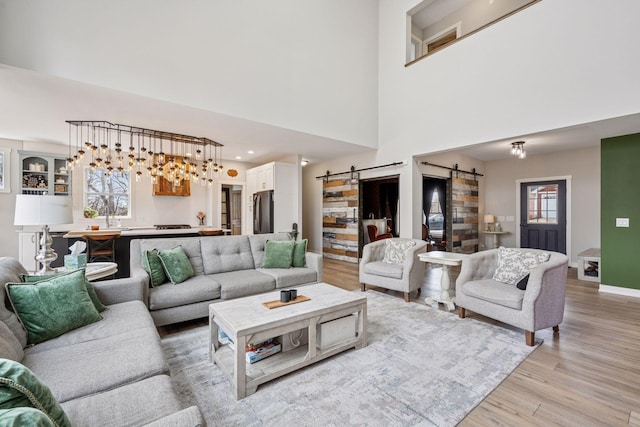 18837 Ogden St NW, Elk River, MN 55330 - living room featuring a barn door, light wood-type flooring, baseboards, and a towering ceiling