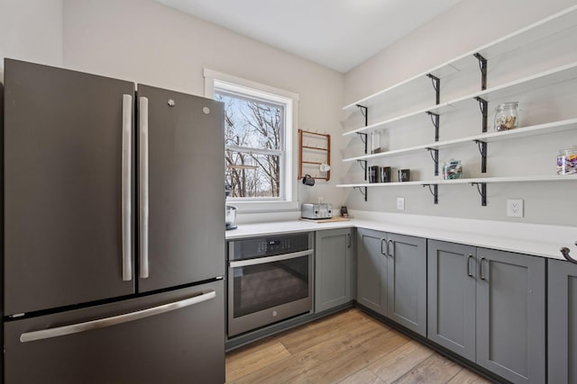 18837 Ogden St NW, Elk River, MN 55330 - kitchen featuring appliances with stainless steel finishes, gray cabinets, light wood finished floors, light countertops, and open shelves