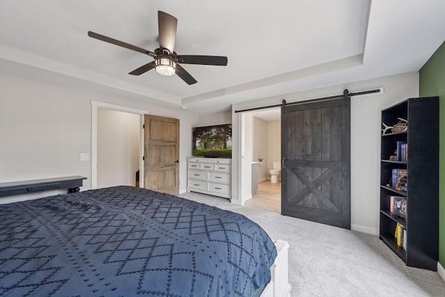 18837 Ogden St NW, Elk River, MN 55330 - bedroom featuring a barn door, light colored carpet, a raised ceiling, ensuite bathroom, and a ceiling fan