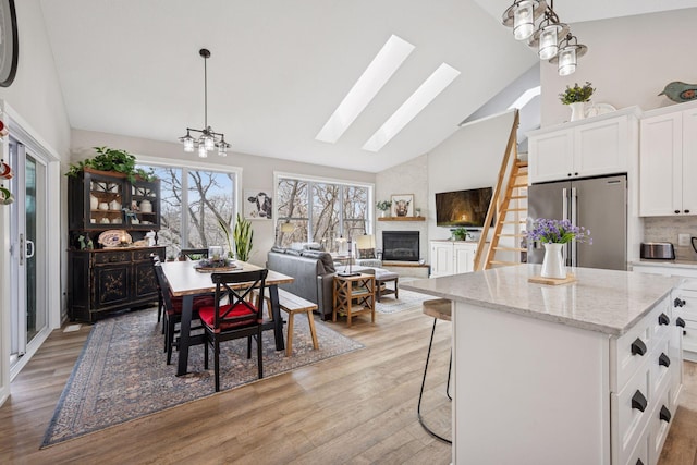 18837 Ogden St NW, Elk River, MN 55330 - dining area featuring high vaulted ceiling, a large fireplace, a skylight, and light wood finished floors