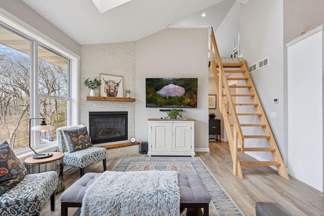 18837 Ogden St NW, Elk River, MN 55330 - living area featuring stairway, light wood-type flooring, a large fireplace, high vaulted ceiling, and baseboards
