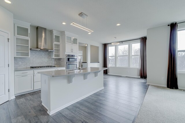 15485 Jersey Ave S, Savage, MN 55378 - kitchen featuring wall chimney range hood, healthy amount of natural light, stainless steel appliances, an island with sink, and recessed lighting