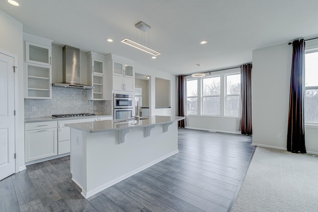 15485 Jersey Ave S, Savage, MN 55378 - kitchen featuring wall chimney range hood, healthy amount of natural light, stainless steel appliances, an island with sink, and recessed lighting