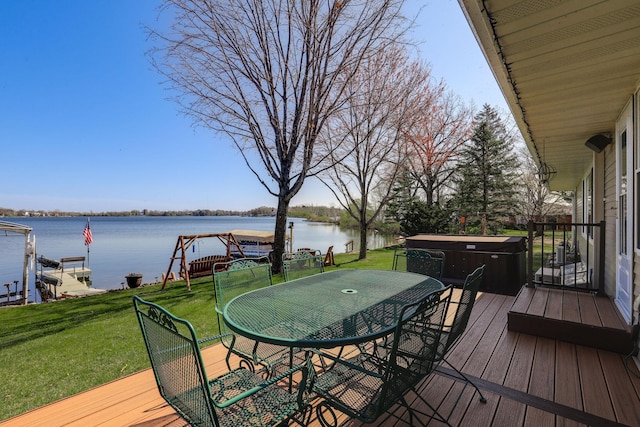 deck with outdoor dining area, a water view, a hot tub, and a yard