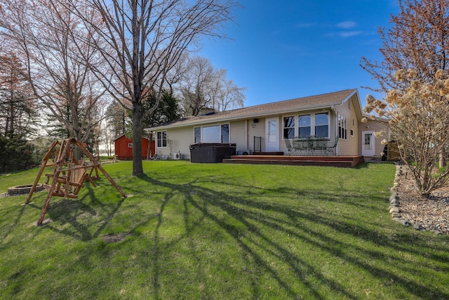 back of house featuring a lawn, a hot tub, a fire pit, and a deck