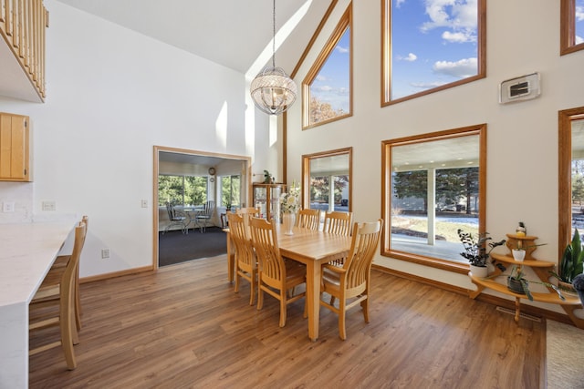 dining space with light wood-type flooring, baseboards, visible vents, a chandelier, and high vaulted ceiling