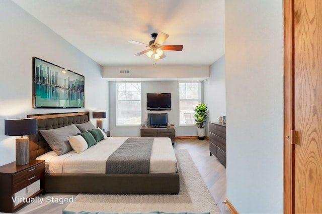 bedroom with light wood-style floors, visible vents, and a ceiling fan