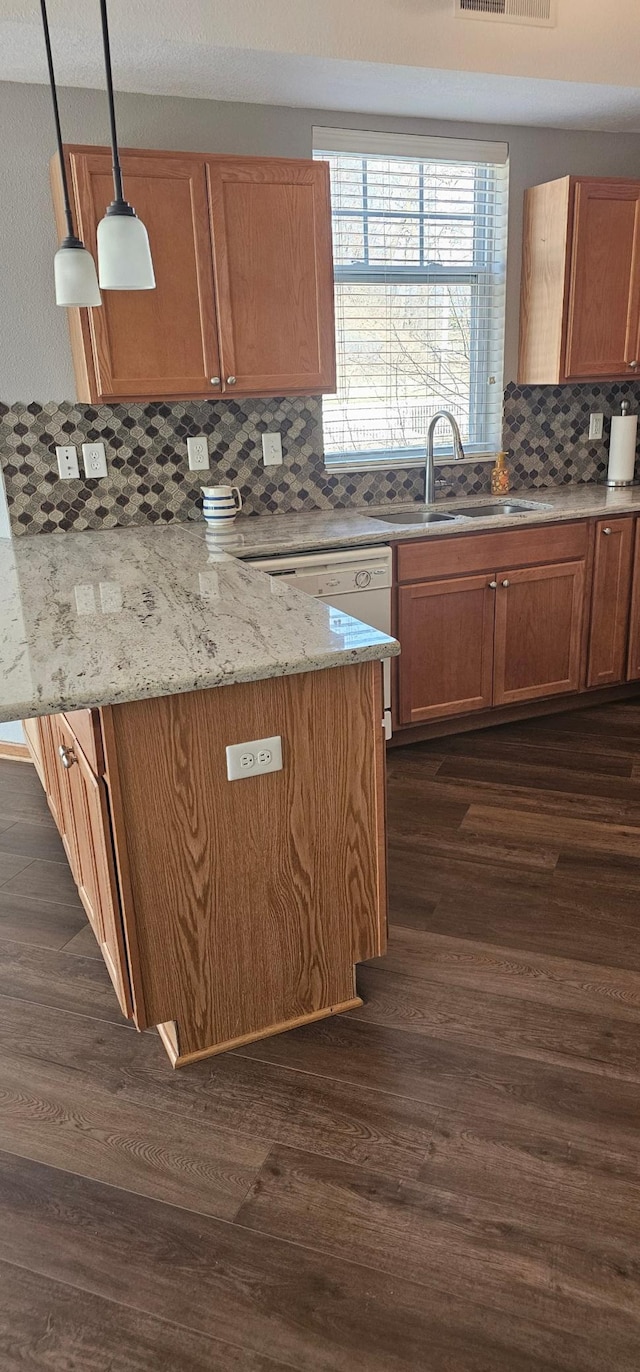 kitchen featuring a sink, light stone counters, tasteful backsplash, and dark wood-type flooring