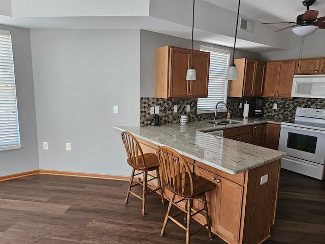 kitchen with white appliances, decorative backsplash, a peninsula, and a sink