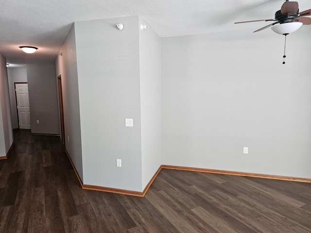 empty room with dark wood finished floors, baseboards, and a ceiling fan