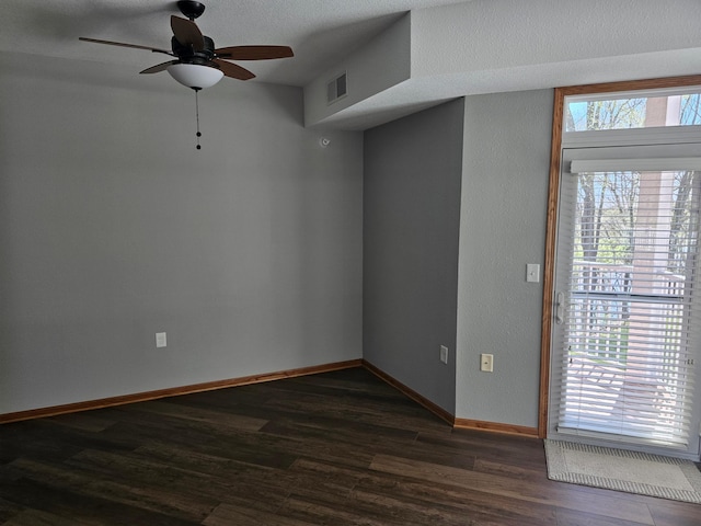 spare room featuring visible vents, baseboards, ceiling fan, and dark wood-type flooring