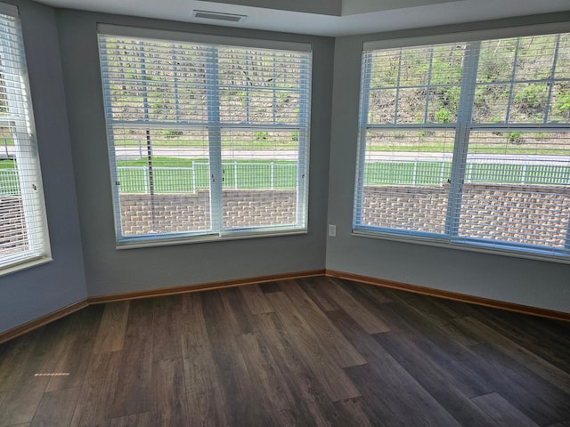 empty room with baseboards, dark wood-style flooring, and visible vents