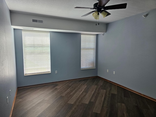 spare room with visible vents, baseboards, a ceiling fan, and dark wood-type flooring