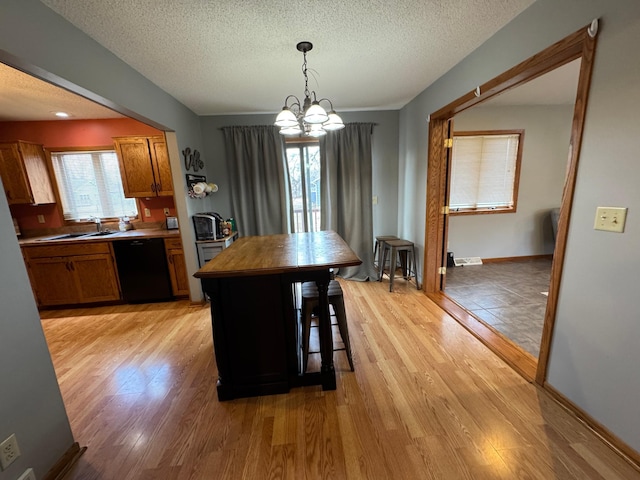 318 Pine Ave S, Sandstone, MN 55072 - kitchen with light wood-style flooring, a textured ceiling, a chandelier, black dishwasher, and brown cabinetry