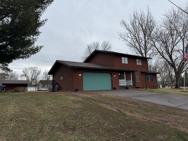 318 Pine Ave S, Sandstone, MN 55072 - chalet / cabin featuring an attached garage, aphalt driveway, a shingled roof, and a front yard