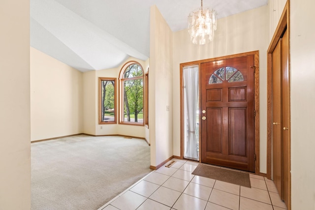 foyer entrance featuring light colored carpet, a chandelier, baseboards, lofted ceiling, and light tile patterned flooring