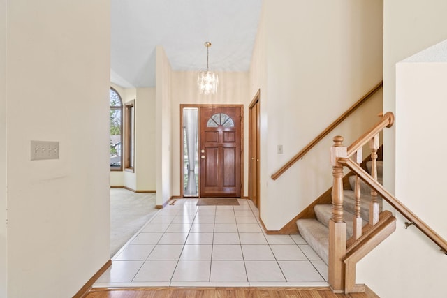 entryway with stairway, a chandelier, baseboards, and light tile patterned floors