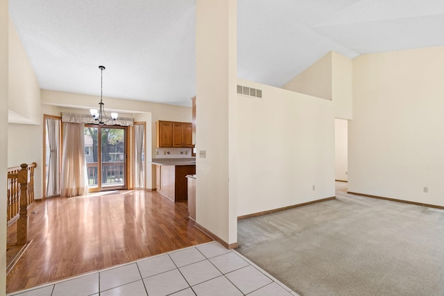 unfurnished living room featuring a chandelier, baseboards, light tile patterned floors, and high vaulted ceiling